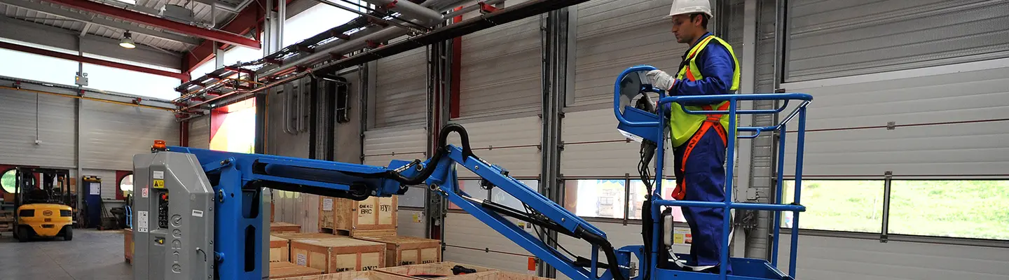 Worker on electric boom lift inside a warehouse