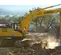 Yellow and gray Kobelco excavator digging rocks and dirt at job site