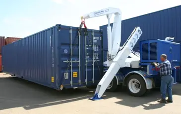 man delivering a blue shipping container with a small crane