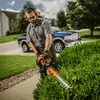 Orange Stihl hedge trimmer with 30 inch blade being used to cut hedges
